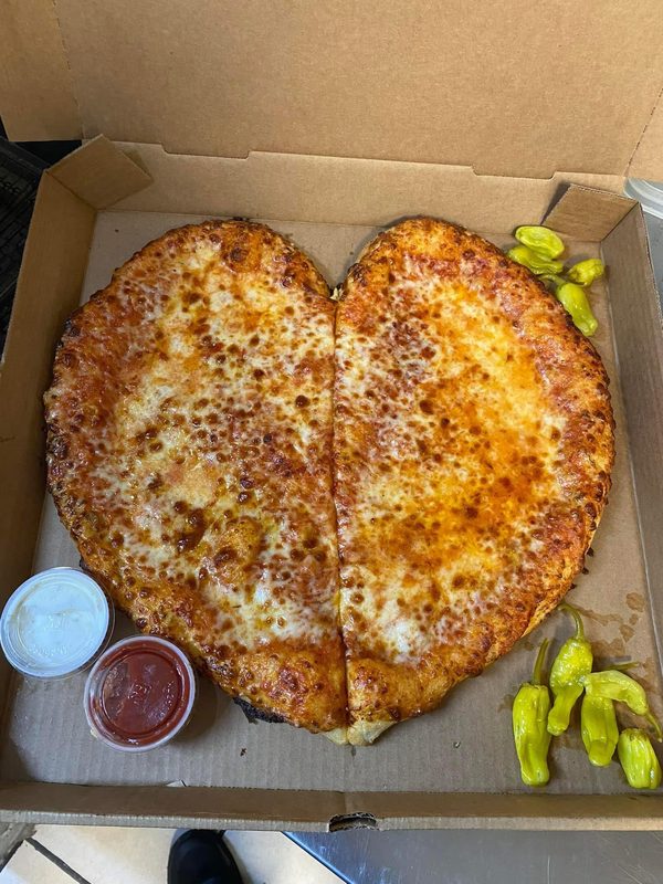 Heart-shaped cheese pizza with pepperoncini and dipping sauces